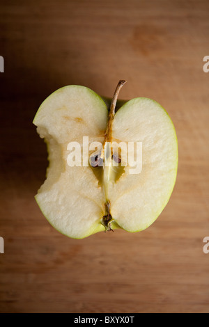 Sliced Granny Smith apple with a bite taken out of it on a wooden cutting board Stock Photo