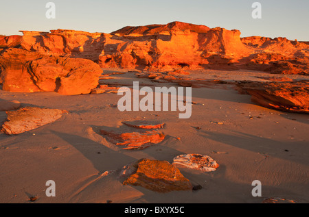Golden sunset on red pindan rocks at Barn Hill Station beach, Broome, Kimberley, Western Australia Stock Photo
