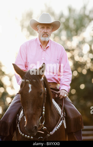 Portrait of senior man horseback riding in ranch Stock Photo