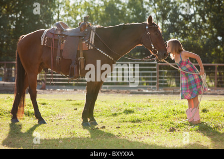 Cowgirl kissing horse in ranch Stock Photo