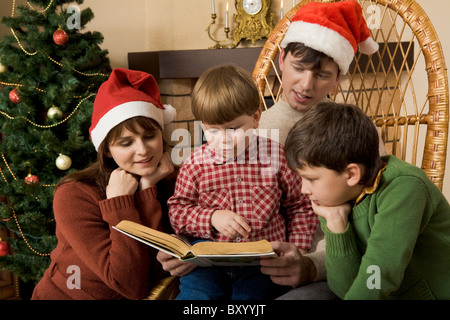 Little boy surrounded by his family members trying to read book Stock Photo