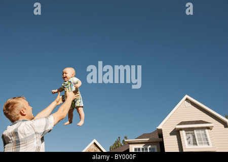 Father lifting baby boy outside home Stock Photo