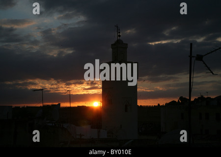 a silhouette of the city of fez in morocco with millions of swallows flying in the evening sunset with a mosque in the foregroun Stock Photo