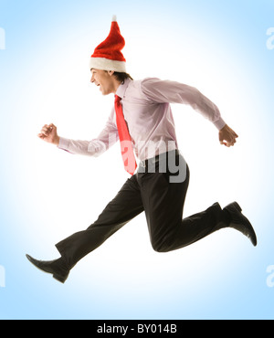 Profile of joyful business Santa jumping high over blue background Stock Photo