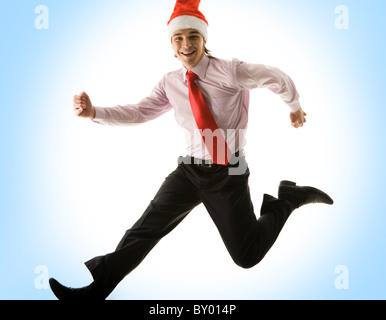 Photo of happy man in santa cap running somewhere over blue background Stock Photo