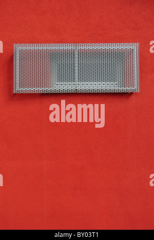 window with metal grille and red wall Stock Photo