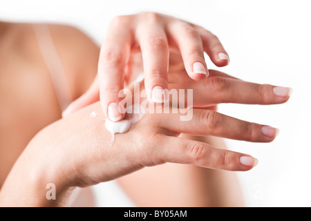 Smiling young woman applies cream on her hands. On a white background. Stock Photo
