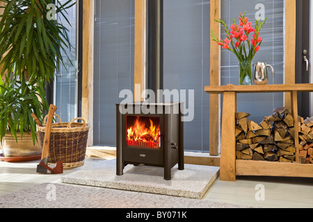 A wood burning stove in an oak framed building with log store Stock Photo