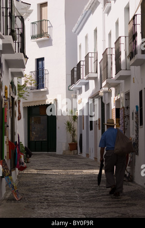 OLD MAN WITH HAT AND SACK ON HIS BACK WALKING DOWN A COBBLED STREET IN FRIGLIANA COSTA DEL SOL ANDALUCIA SPAIN Stock Photo