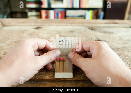 Person holding matchbook with phone number written on it Stock Photo