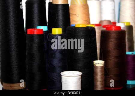 A large group of cotton threads including black, brown, white, cream and dark blue Stock Photo