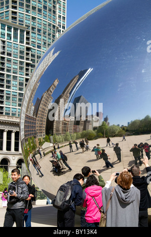 Visitors look at their reflection in the Cloud Gate sculpture located at the AT&T Plaza in Millennium Park, Chicago, Illinois. Stock Photo