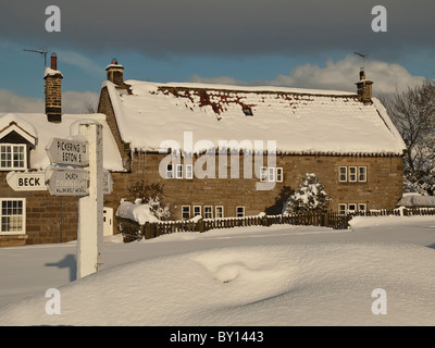 Cottage and sign post in deep snow Goathland, North Yorkshire. Stock Photo