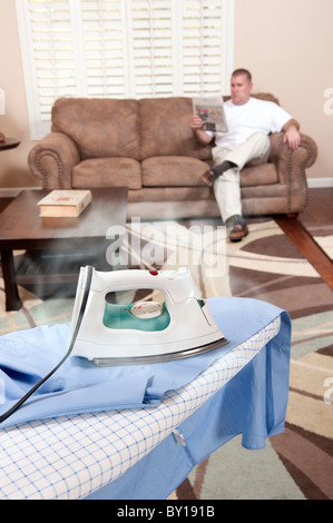 A man sit on his couch while the iron burns and scorches his dress shirt. Stock Photo