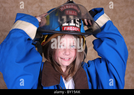 A young girl dressed up as a firewoman in firefighting gear holding her helmet Stock Photo