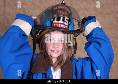 A young girl dressed up as a firewoman in firefighting gear holding her helmet Stock Photo