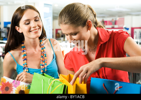 Photo of two friends looking through their shoppings with smiles in the mall Stock Photo