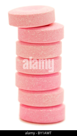 Seven pink antacid tablets stacked in a row on white background. Stock Photo