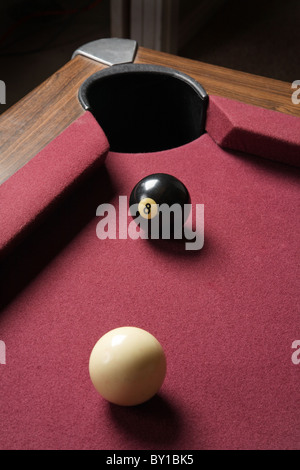 cue and eight ball lined up close on pool table corner pocket Stock Photo