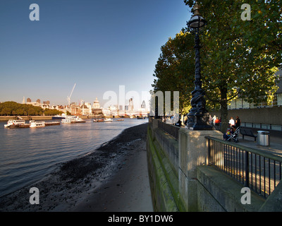 The Queen's walkway near Gabriels Wharf along the river Thames with people walking under the trees. Stock Photo