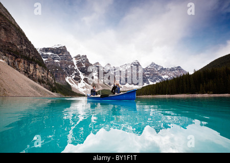 Man and woman sailing on peaceful lake against mountain range Stock Photo