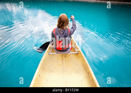 Rear view of woman rowing boat on calm water Stock Photo