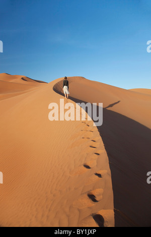 Oman, Empty Quarter. A young lady makes her way up the steep dunes. MR. Stock Photo
