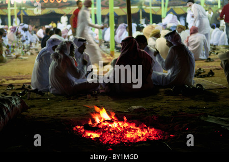 Small group of guests converse near fire during traditional Bedouin wedding celebration. El Tur, Sinai Peninsula, Egypt Stock Photo