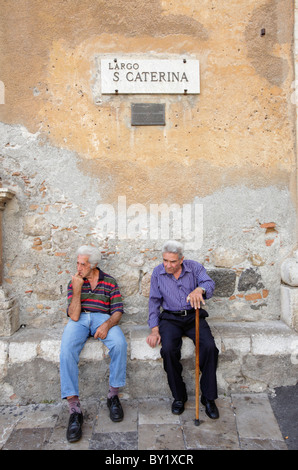 Old men sitting on a bench in a square, Taormina, Italy Stock Photo