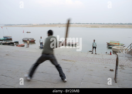 Young men playing cricket on the banks of the Ganges in India Stock Photo