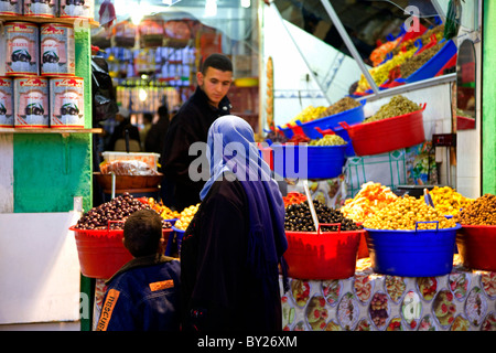 Tripoli, Libya, Tripolitania; A woman with her son at the Tripoli market in an outlet selling olives of different kinds, just Stock Photo