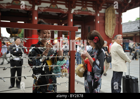 Young Japanese women dressed in kimonos knotting and reading horoscopes at Sanja Matsuri, Asakusa, Tokyo, Japan Stock Photo