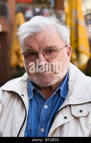 Elderly man sitting at sidewalk cafe, serious, looking at camera Stock Photo