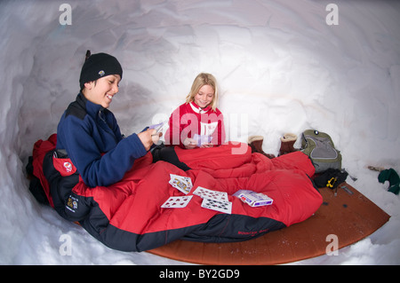 Boy and girl playing cards in snowcave, Red Mountain Pass, San Juan National Forest, Colorado (fisheye lens). Stock Photo