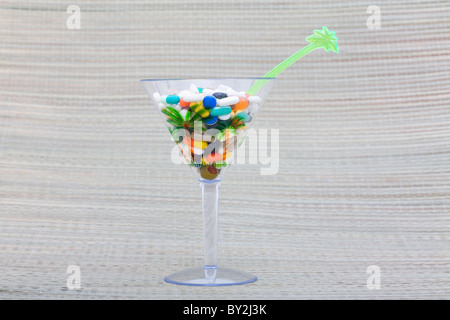 A cocktail of pills in a martini glass on a beach mat Stock Photo
