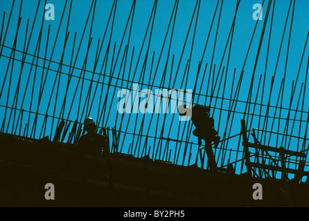 Two construction workers and rebar reinforcing steel silhouetted at commercial construction site in U.S. Stock Photo