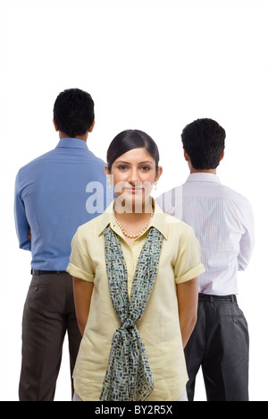 One businesswoman facing the camera and two businessmen facing away from camera Stock Photo