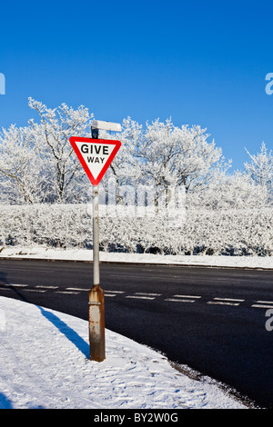 Give way sign on a sunny, snow covered winter day Stock Photo