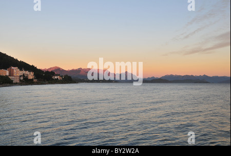 Sunrise red glow on Cerro Lopez and Andean peaks, across the morning waters of Lake Nahuel Huapi, Bariloche, Argentina Stock Photo