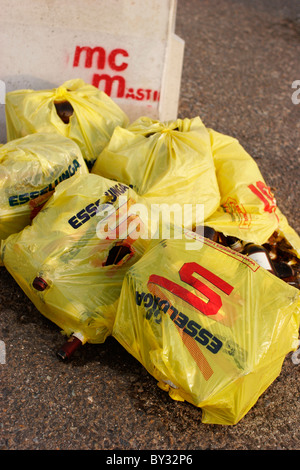 Garbage bags left on the ground. A lot of beer bottle on the road. Stock Photo