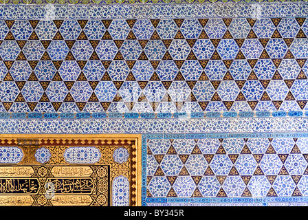 Topkapi Palace Audience Chamber Ceramic Tiles Istanbul | ISTANBUL, Turkey — Geometric star patterns of İznik tile cover a wall of the Audience Chamber, or Arz Odası, at Topkapi Palace, bordering a gilded calligraphic panel that once framed the throne room where sultans met foreign envoys. The interlocking triangle and hexagon motifs, filled with cobalt-blue floral scrollwork, exemplify the disciplined geometric side of Ottoman İznik ceramic design. Stock Photo