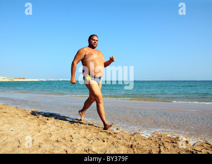 sport - overweight man running on sea coastline Stock Photo