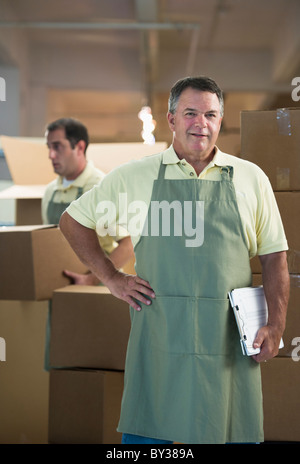 USA, New Jersey, Jersey City, Portrait of male warehouse worker by stacked boxes Stock Photo