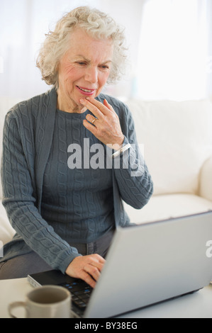 USA, New Jersey, Jersey City, Senior woman using laptop in living room Stock Photo