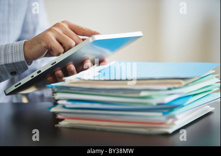 USA, New Jersey, Jersey City, Businessman using digital tablet by paperwork Stock Photo