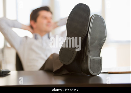 USA, New Jersey, Jersey City, Businessman with feet up on desk Stock Photo
