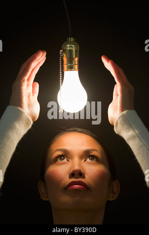 Woman looking up at illuminated lightbulb Stock Photo