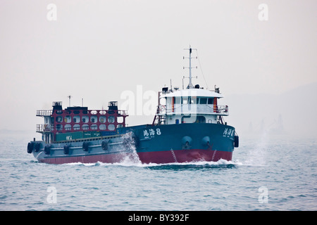 Cargo container ship Hong Hai in Victoria Harbour between Kowloon and Hong Kong Island on typical hazy day. JMH4141 Stock Photo