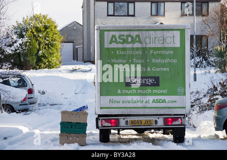 UK, Britain. Asda home delivery van outside a house delivering online shopping with snow on residential street in winter Stock Photo