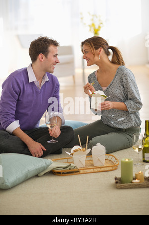 USA, New Jersey, Jersey City, Portrait of young couple eating takeaway food on floor Stock Photo